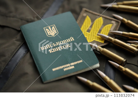 Military token or army ID ticket lies on green ukrainian military uniform indoors close up 113832074