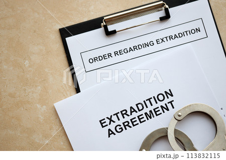 Extradition Agreement and Order Regarding Extradition with handcuffs on table close up Extradition Agreement and Order Regarding Extradition with handcuffs on table close up 113832115