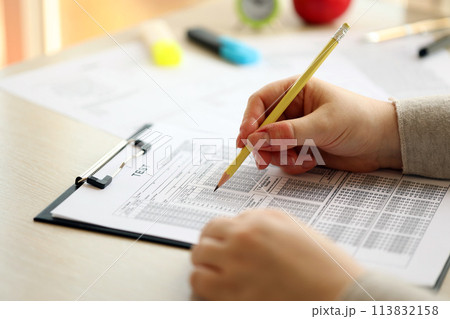Female student hands testing in exercise and taking fill in exam paper sheet with pencil at school test room, education concept Female student hands testing in exercise and taking fill in exam paper sheet with pencil at school test room, education concept 113832158