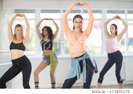 During lesson, girl learn to move and perform dance in heels with women companions During lesson, girl learn to move and perform dance in heels with women companions 113835178