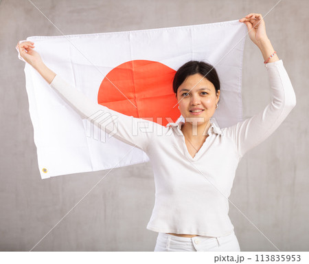 Smiling female fan of Japan cheers for winning holding flag 113835953