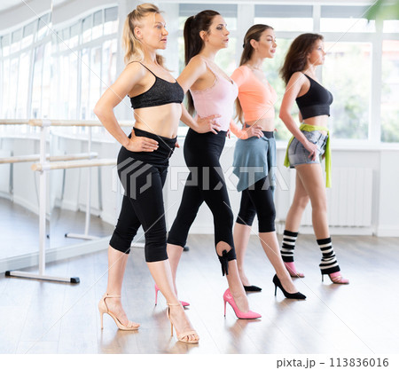 Female participants of project stand in row and perform dance in heels. 113836016