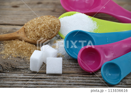 Measuring utensils and spilled sugar on rustic wood 113836616