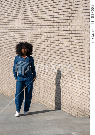 Trendy Woman in Denim Attire Against Brick Wall Trendy Woman in Denim Attire Against Brick Wall 113837083
