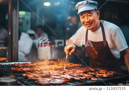Happy Asian chef cooking traditional food on open fire in street market Happy Asian chef cooking traditional food on open fire in street market 113837535