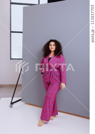 A woman is sitting on a wooden chair in a room with white walls A woman is sitting on a wooden chair in a room with white walls 113837705