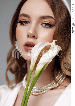 A woman with long brown hair and a white flower in her mouth 113837711