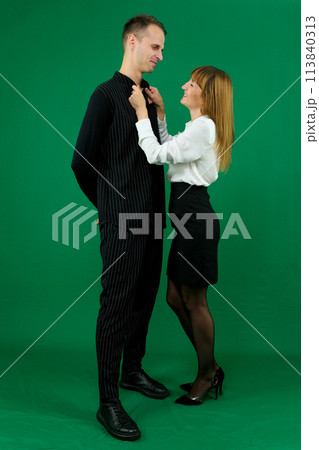 Young attractive business people in formal wear looking at each other. On a green background In a studio. Photo 113840313