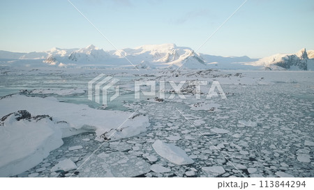 Sunrise over Antarctic coast. Aerial view. Ocean covered melting ice. Antarctica above snow mountain. Winter open water. Beautiful sky landscape. Top Drone Flight 113844294
