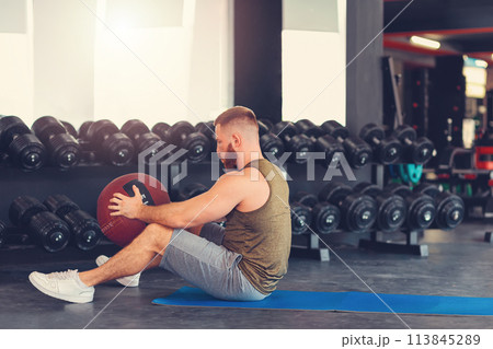 Bearded athletic man training in the gym with a sports ball. Side view. Copy space. The concept of fitness Bearded athletic man training in the gym with a sports ball. Side view. Copy space. The concept of fitness 113845289