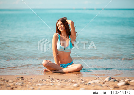 Summer vacation concept. A young pretty caucasian woman sitting crossed legs on the oceans beach 113845377