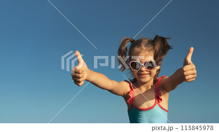 Portrait of laughing girl of 6 years in blue swimsuit and heart-shaped sunglasses gesturing super, fine against blue sky, banner Portrait of laughing girl of 6 years in blue swimsuit and heart-shaped sunglasses gesturing super, fine against blue sky, banner 113845978