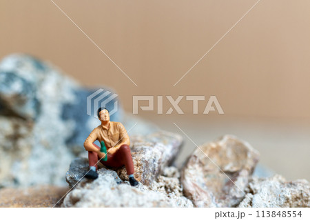 Miniature people , A young man sipping beer while sitting on the rock 113848554