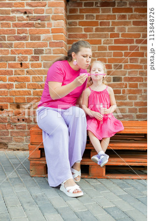 Deaf child with cochlear implant for hearing audio and aid for impairment having fun and laughs with mother outdoor in summer. Sound fitting device to help with communication listening and interaction Deaf child with cochlear implant for hearing audio and aid for impairment having fun and laughs with mother outdoor in summer. Sound fitting device to help with communication listening and interaction 113848726
