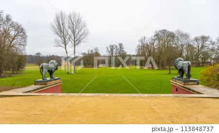 Overlooking a lush green lawn flanked by stone lion statues in Bad Muskau renowned park. Saxony, Germany 113848737