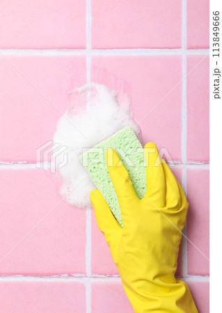 Washing pink tiles in rubber gloves close-up 113849666