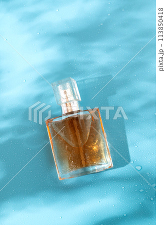A perfume bottle on a blue background with hard shadows. Flat Lay and hard light 113850418