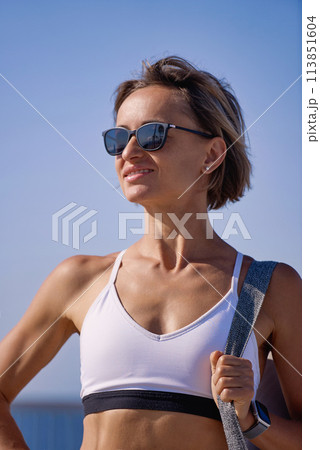 A young girl in sportswear is going to workout with a fitness mat 113851604