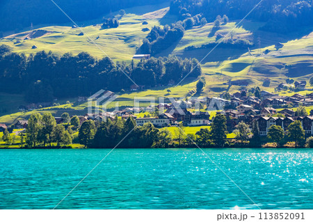 Swiss village Lungern with traditional houses, old church Alter Kirchturm along lovely emerald green lake Lungerersee, canton of Obwalden Switzerland Swiss village Lungern with traditional houses, old church Alter Kirchturm along lovely emerald green lake Lungerersee, canton of Obwalden Switzerland 113852091