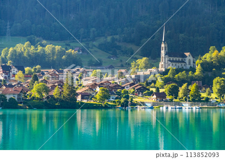 Swiss village Lungern with traditional houses, old church Alter Kirchturm along lovely emerald green lake Lungerersee, canton of Obwalden Switzerland Swiss village Lungern with traditional houses, old church Alter Kirchturm along lovely emerald green lake Lungerersee, canton of Obwalden Switzerland 113852093