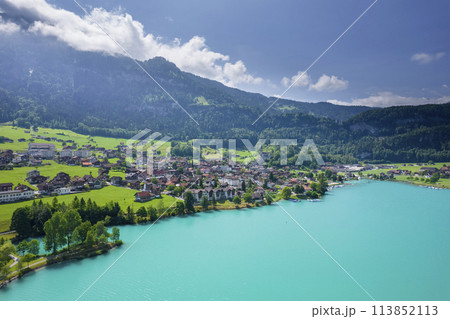 Aerial of Swiss village Lungern with traditional houses, old church Alter Kirchturm along lovely emerald green lake Lungerersee, canton of Obwalden Switzerland Aerial of Swiss village Lungern with traditional houses, old church Alter Kirchturm along lovely emerald green lake Lungerersee, canton of Obwalden Switzerland 113852113