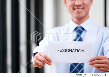 Smiling man displays resignation letter, suggesting a hopeful new beginning. 113853361