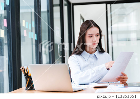 Focused Businesswoman Analyzing Document in Office 113853651