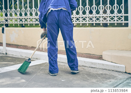 A municipal employee in a blue uniform collects garbage from roads and sidewalks. City cleaning Service with copy space. High quality photo 113853984