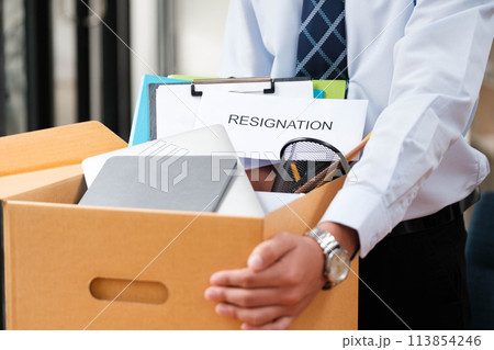 Man places personal items and resignation letter into a box, ending his tenure. Man places personal items and resignation letter into a box, ending his tenure. 113854246