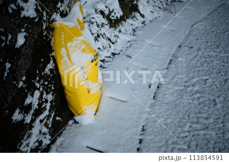 雪道に置かれた塩化カルシウムの袋 113854591