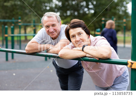 Elderly man and woman posing in open-air sports bars complex Elderly man and woman posing in open-air sports bars complex 113858735
