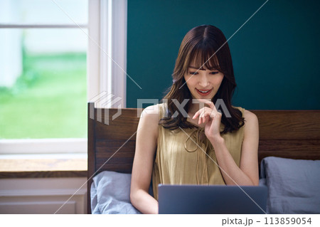 寝室でパソコンを操作する若い女性 寝室でパソコンを操作する若い女性 113859054