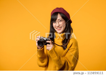 In her quest to capture life's beauty, a young Asian woman, donning a yellow sweater and red beret, skillfully wields her camera as a talented photographer. In her quest to capture life's beauty, a young Asian woman, donning a yellow sweater and red beret, skillfully wields her camera as a talented photographer. 113859111
