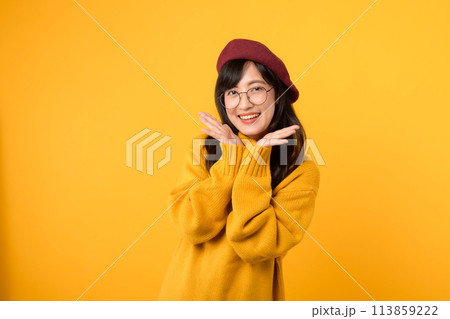 Joyful and a touch of shyness. A charming girl, donning a red beret and yellow sweater, expresses happiness against a vibrant yellow background. Joyful and a touch of shyness. A charming girl, donning a red beret and yellow sweater, expresses happiness against a vibrant yellow background. 113859222