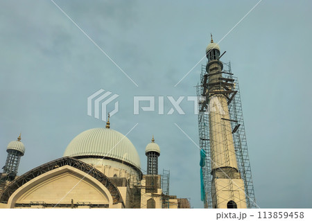 The process of building a new large mosque with several minarets. Exterior decoration works at height with the help of industrial scaffolding 113859458