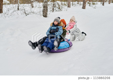 Girl pushing snow tube with friends Girl pushing snow tube with friends 113860208