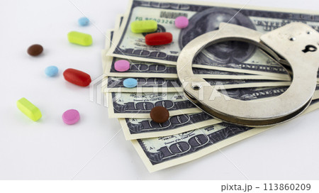 metal handcuffs with money and drugs on a white background metal handcuffs with money and drugs on a white background 113860209