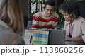 African American businessman talking to female colleague while lady designer working with laptop in creative office. Start-up and coworking concept. 113860256