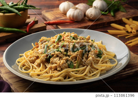 Stir fried spicy spaghetti with minced chicken breast and basil leaves in white plate,Spicy pasta Pad Kra Pao.Healthy Thai fusion food 113861396