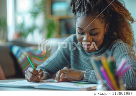 happy dark-skinned woman drawing with pencils in colouring book 113861987