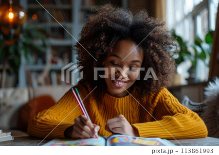 happy dark-skinned woman drawing with pencils in colouring book 113861993
