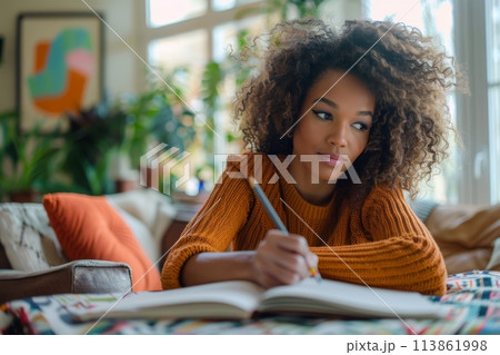 happy dark-skinned woman drawing with pencils in colouring book 113861998