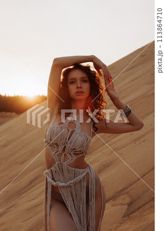 Sexy woman in a rope dress poses on a sandy hillside. 113864710
