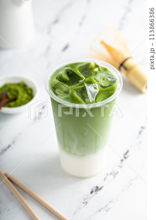 Matcha iced latte in a tall glass with matcha tea over milk 113866386