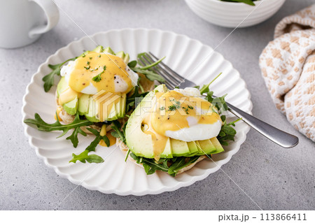English muffins with arugula, avocado and poached eggs, healthy eggs benedict English muffins with arugula, avocado and poached eggs, healthy eggs benedict 113866411