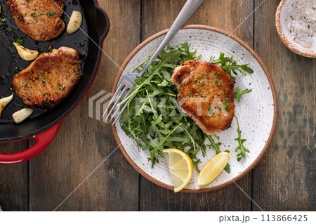 Pork chops served with arugula salad on a plate Pork chops served with arugula salad on a plate 113866425