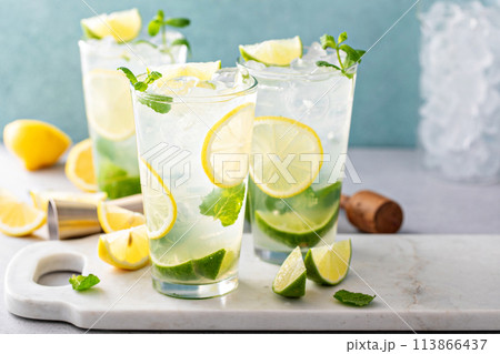 Cold refreshing mojito with lemon and lime and mint in tall glasses Cold refreshing mojito with lemon and lime and mint in tall glasses 113866437