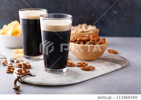 Dark stout beer in tall glasses with snacks 113866560