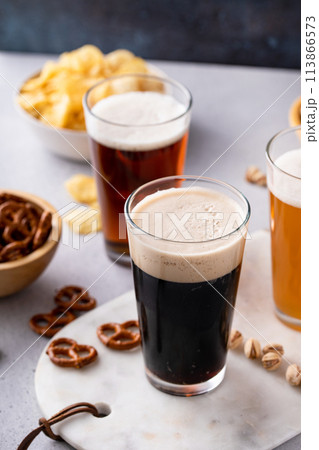 Dark stout, lager and ale beer in tall glasses on the table with snacks 113866573