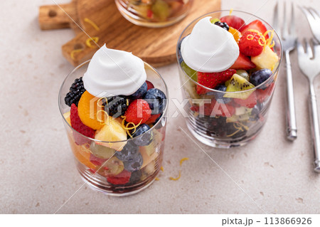 Fruit salad served in individual cups with banana, pineapples, berries, orange dressing and mint 113866926
